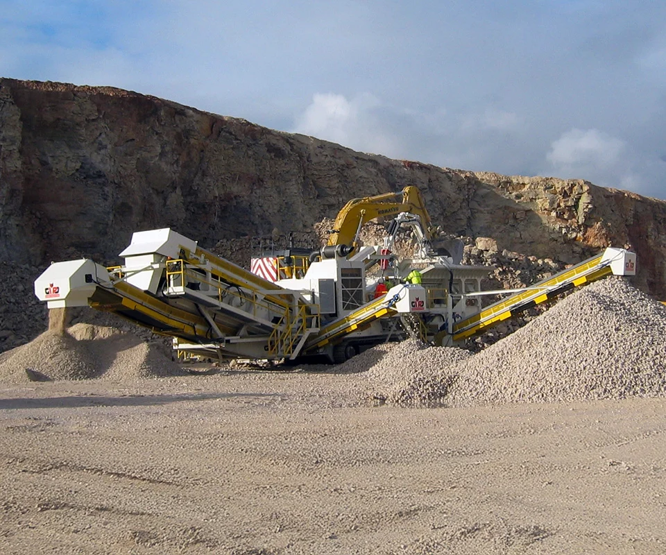 Gipo P170 mobile Prallbrechanlage im Steinbruch, vom Bagger beschickt; Förderbänder bilden Halden aus gebrochenem Gestein.