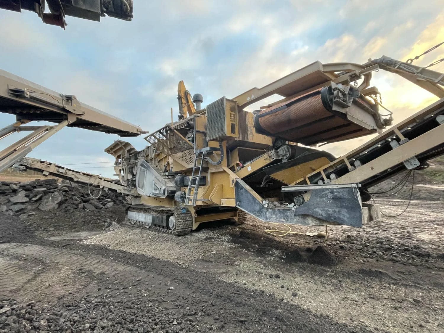 Unité mobile de concassage et de criblage sur chenilles en fonctionnement sur un site de carrière.